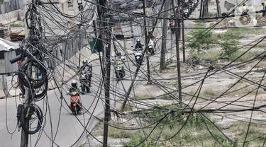 Kendaraan melintas dekat instalasi kabel yang semrawut di Jalan Raya Bekasi, Cakung, Jakarta, Rabu (30/9/2020). Minimnya perawatan pascapembebasan lahan permukiman untuk proyek Tol Dalam Kota membuat jaringan kabel listrik di sepanjang jalan tersebut semrawut. (merdeka.com/Iqbal S. Nugroho)