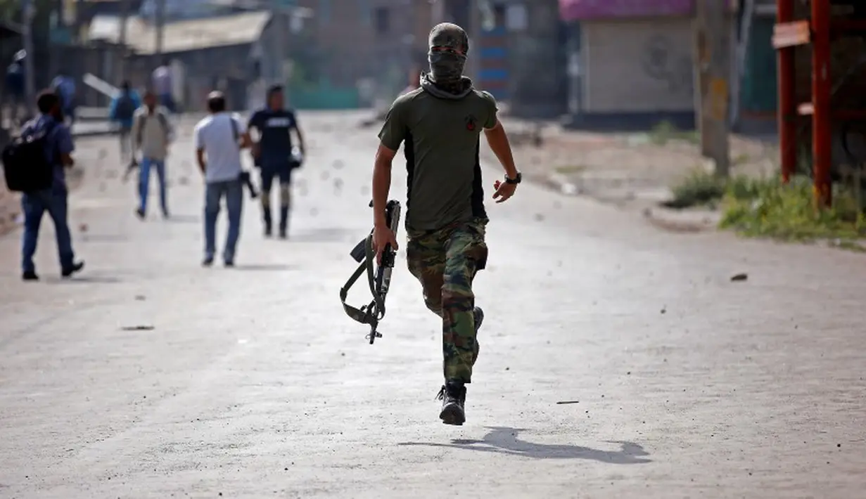 Seorang polisi mengenakan penutup wajah saat aksi protes terjadi di Srinagar, India, Selasa (13/9). Demonstran protes karena pembunuhan yang terjadi di Kashmir belum lama ini. (REUTERS / Danish Ismail)