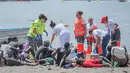 Foto selebaran yang dirilis oleh Palang Merah Spanyol (Cruz Roja) pada 13 Juli 2023 menunjukkan anggota Palang Merah dan responden pertama merawat orang-orang setelah sebuah kapal tiba dengan 41 migran di dalamnya, di pantai Las Galletas di kotamadya Arona, di Pulau Canary Tenerife. (Handout / SPANISH RED CROSS / AFP)