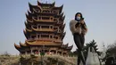 Seorang perempuan bermasker mengunjungi Menara Bangau Kuning yang ikonik di Wuhan di provinsi Hubei, China, Jumat (15/1/2021). Selain masker, orang-orang menjalani kehidupan sehari-hari mereka seperti sebelumnya di Wuhan, tempat pertama kali virus corona COVID-19 terdeteksi. (AP Photo/Ng Han Guan)