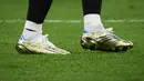 Sepatu Lionel Messi itu sebagian besar berwarna emas, dengan biru dan putih mewakili warna bendera Argentina. Ada pula garis hitam di bagian belakang dan tiga garis putih corak khas Adidas. (AFP/Franck Fife)