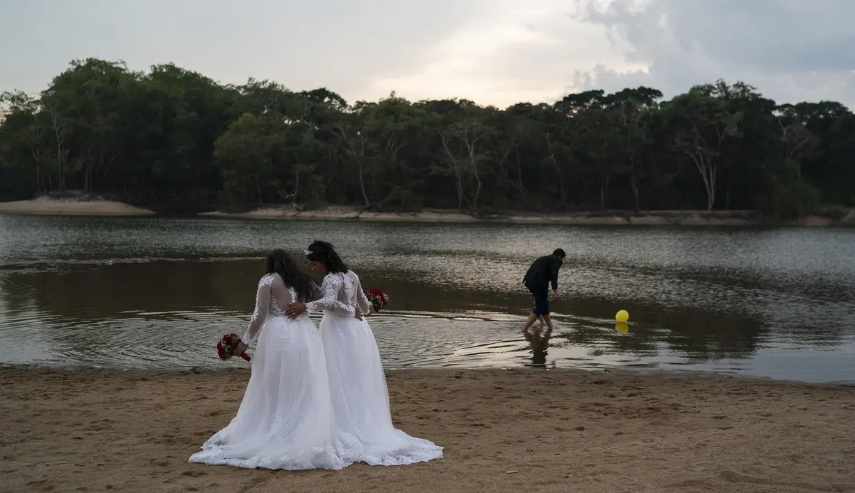 Jaiane Pereira Marsal dan Gislaine Pereira de Araujo bersiap difoto untuk album pernikahan dengan latar belakang hutan hujan Amazon di pantai sungai Jamanxim, Brasil (2/9/2019). Jaiane dan Gislaine akan menikah hari Senin ini dan ibunya merayakan ultah pernikahan ke-25. (AP Photo/Leo Correa)