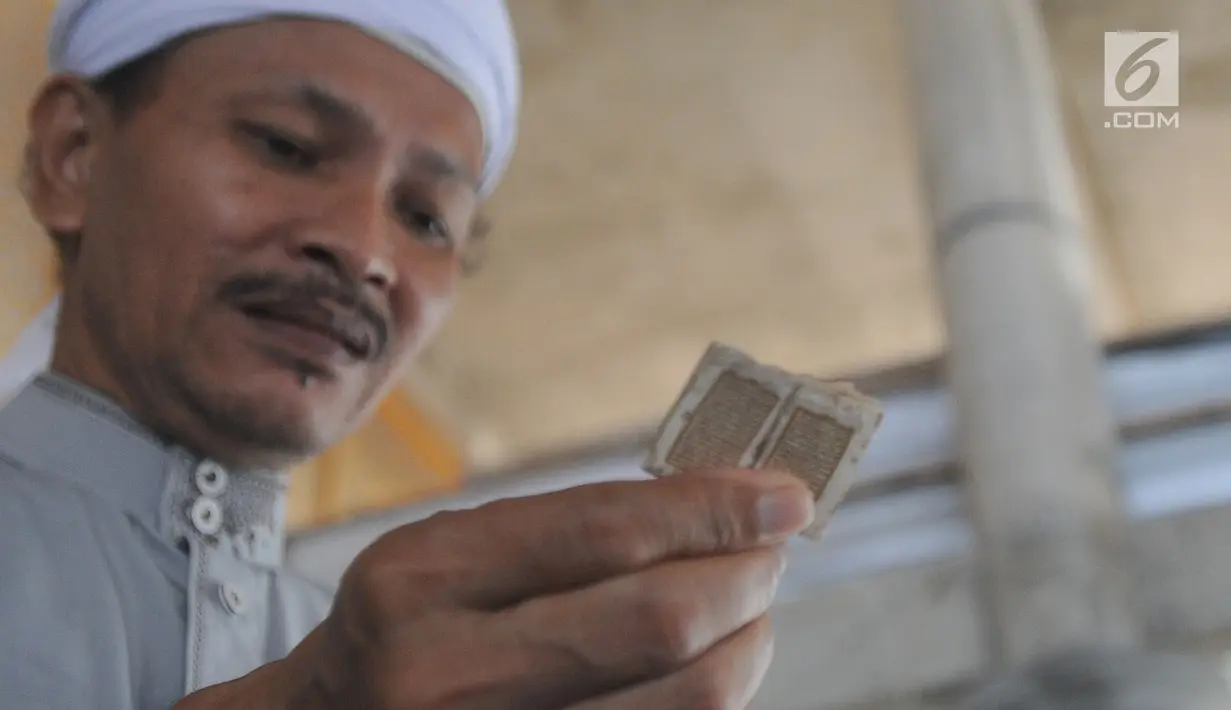 Kyai Tubagus Muhammad Tamyiz menunjukkan Alquran mini di Masjid Jami Darusalam, Sukaraja, Bogor, Kamis (24/5). Alquran mini itu seluruh aksaranya ditulis tangan menggunakan tinta emas serta ditulis di atas lembaran kulit kayu. (Merdeka.com/Arie Basuki)