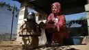 Seorang wanita menggunakan kayu pomace (ampas) sebagai bahan bakar untuk memasak di rumahnya di Kota Khan Younis, Jalur Gaza, Palestina, 7 November 2020. Pekerja Palestina mengubah limbah produksi minyak zaitun menjadi kayu pomace yang dapat digunakan sebagai bahan bakar. (Xinhua/Rizek Abdeljawad)