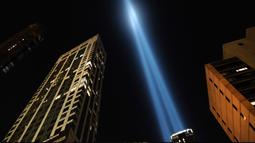 Instalasi cahaya bertajuk 'Tribute in Light'  menembak langit New York City pada Selasa (10/9/2019). Cahaya kembar berwarna biru tersebut dinyalakan untuk memperingati 18 tahun peristiwa serangan gedung kembar World Trade Center (WTC)  pada 11 September 2001 silam. (Spencer Platt/Getty Images/AFP)