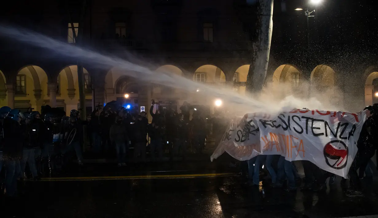 Aktivis antifasis melindungi diri mereka saat ditembakan meriam air oleh petugas keamanan setempat saat menggelar demonstrasi di Turin, Italia (22/2). (AFP Photo/Piero Cruciatti)