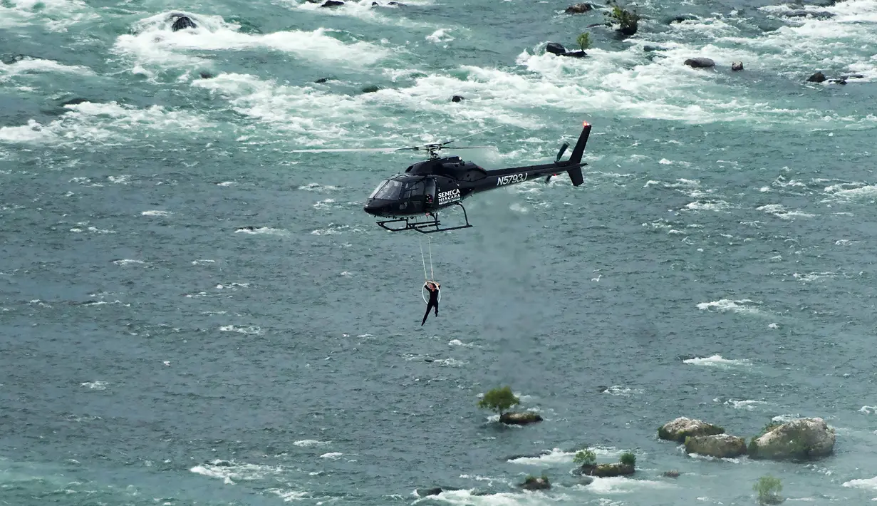 Erendira Wallenda melakukan aksi akrobatik di atas air terjun Niagara, New York, Kamis (15/6). Erendira ditambatkan ke lingkaran besi yang dikaitkan pada helikopter yang terbang 91 meter di atas permukaan air. (Nathan Denette/The Canadian Press via AP)