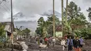 Orang-orang berjalan di tanah yang tertutup abu vulkanik setelah aliran piroklastik selama letusan Gunung Semeru di Desa Supiturang, Lumajang, Jawa Timur pada Kamis 20 November 2025. Gunung Semeru kembali mengalami erupsi pada Rabu (19/11/2025) sore. (Agus Harianto/AFP)