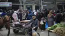 Tahun 2026 menjadi yang ketiga masyarakat Gaza merayakan Idul Fitri di tengah situasi konflik yang berkepanjangan sejak Oktober 2023. Tampak dalam foto, seorang anak laki-laki Palestina yang mengungsi mengendarai sepeda sementara orang-orang berbelanja di kios-kios di pasar jalanan sekitar kamp pengungsi Nuseirat, Jalur Gaza tengah, pada Rabu 18 Maret 2026. (Eyad Baba/AFP)