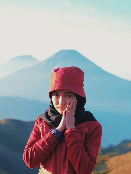 Saat mendaki Gunung Prau, gadis yang berusia 22 tahun ini tidak lupa untuk berfoto dengan pemandangan indah pegunungan. Gayanya tampak imut dengan jaket berwarna merah dan topi dengan warna senada. (Liputan6.com/IG/@arafahrianti)