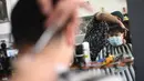 Seorang tukang cukur memotong rambut kliennya di sebuah salon di London, Inggris, Senin (12/4/2021). Inggris melonggarkan pembatasan terkait virus corona COVID-19. Inggris melonggarkan pembatasan terkait virus corona COVID-19. (Photo by DANIEL LEAL-OLIVAS/AFP)