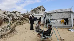 Pembentukan dua badan tersebut dinyatakan dalam sebuah pernyataan pada Jumat (16/1/2026). Tampak dalam foto, para pengungsi Palestina yang tinggal di antara reruntuhan rumah dan bangunan yang hancur akibat serangan militer Israel selama lebih dari dua tahun di wilayah Gaza, bermain ayunan di luar tenda mereka, di kamp pengungsi Jabalia, di bagian utara Jalur Gaza pada Sabtu 17 Januari 2026. (Omar AL-QATTAA/AFP)