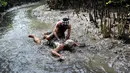 Seorang pria Bali bermain lumpur bersama temannya selama tradisi mandi lumpur atau dikenal sebagai Mebuug-buugan di desa Kedonganan, Denpasar, Bali (10/3). Mebuug-buugan diadakan sehari usai hari raya Nyepi. (AFP/Sonny Tumbelaka)