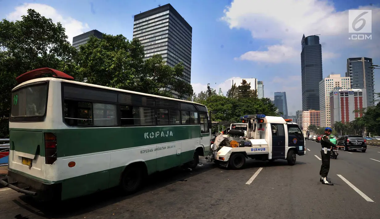 Petugas Dinas Perhubungan (Dishub) DKI Jakarta menderek bus Kopaja yang ngetem di kawasan Stasiun Sudirman, Jakarta (17/7). Razia ini digelar untuk menyambut Asian Games Agustus mendatang. (Merdeka.com/Arie Basuki)