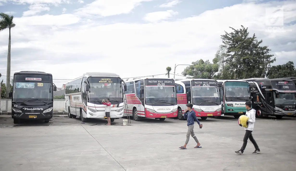 Dua pria melintasi bus yang terparkir di Terminal terpadu tipe A Pondok Cabe di Pamulang, Tangerang Selatan, Senin (31/12). Mulai 31 Desember , terminal yang memiliki luas mencapai 25.995 m2 tersebut resmi beroperasi. (Liputan6.com/Faizal Fanani)