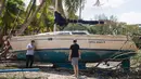 Dua orang pria berdiri dekat sebuah kapal yang terhempas ke daratan akibat terhempas badai Irma di Coconut Grove, Florida, Senin (11/9).Badai Irma menghantam negara bagian Florida dengan kecepatan angin mencapai 200 km/jam. (SAUL LOEB/AFP)