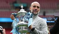 Manajer Manchester City, Pep Guardiola, berpose dengan trofi di lapangan setelah pertandingan final Piala FA Inggris antara Chelsea melawan Manchester City di Stadion Wembley, London, pada 16 Mei 2026. City memenangkan pertandingan dengan skor 1-0. Gelar FA Cup ketiga pada era kepelatihan Guardiola tersebut mengakhiri rentetan dua kekalahan beruntun City di partai final. (Adrian Dennis / AFP)