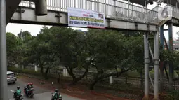 Pengendara melintasi bawah Jembatan Penyeberangan Orang (JPO) di Jalan Raya Lenteng Agung, Jakarta, Selasa (17/3/2020). Sebuah spanduk berisi ajakan menghindari kerumunan dan kumpul-kumpul untuk mencegah penyebaran virus Corona COVID-19 terpasang di JPO teresebut. (Liputan6.com/Helmi Fithriansyah)