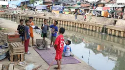 Anak-anak bermain di bantaran anak Sungai Ciliwung, Jakarta, Rabu (6/6). Meskipun tidak layak sebagai tempat bermain, namun lokasi itu menjadi tempat bagi anak-anak di kawasan tersebut untuk menunggu waktu berbuka. (Liputan6.com/Immanuel Antonius)