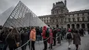 Pengunjung mengantre di luar Pyramid, pintu masuk utama menuju museum Louvre, di Paris, Rabu (4/3/2020). Louvre di Paris, museum yang paling banyak dikunjungi di dunia, kembali dibuka setelah pegawai yang khawatir dengan penularan virus corona setuju kembali masuk kerja. (Philippe LOPEZ/AFP)