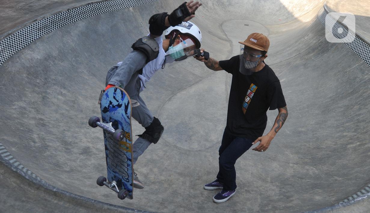 Instruktur melatih seorang anak menggunakan skateboard dengan memakai masker dan face shield di Crooz Shophouse di kawasan Duren Tiga, Jakarta Selatan, Minggu (2/8/2020). Mereka kembali melakukan latihan seminggu dua kali dengan menerapkan protokol kesehatan. (merdeka.com/Arie Basuki)