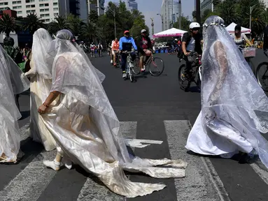 Sejumlah wanita mengenakan gaun dan kerudung putih  dengan noda darah melintas di jalan Mexico City, Meksiko (7/5). Mereka mengenakan pakaian tersebut untuk menggelar aksi "Las 43 Lloronas". (AFP Photo/Yuri Cortez)