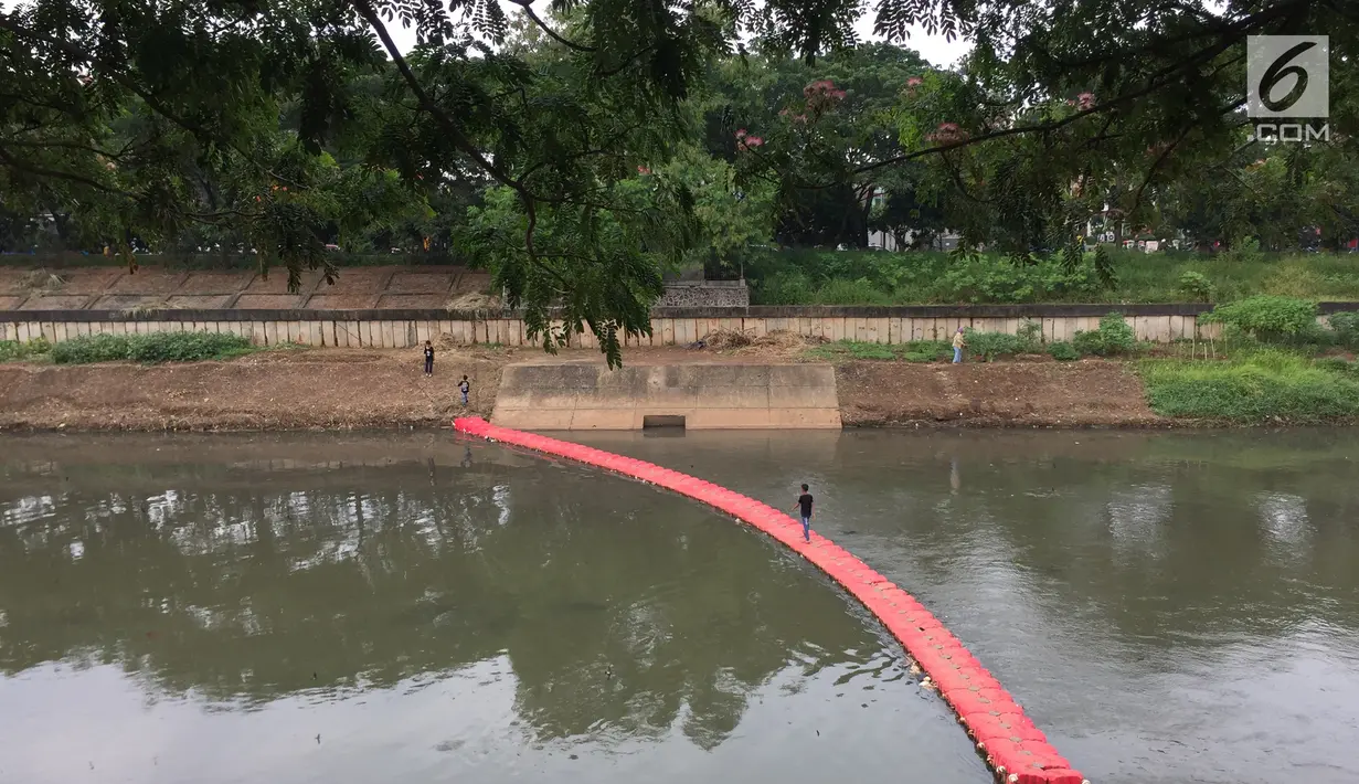 Seorang anak melintasi penyaring sampah untuk menyeberangi Kanal Banjir Timur di Jakarta, Kamis (28/12). Meski tidak aman bagi keselamatan, warga memanfaatkan penyaring sampah tersebut untuk menyebrang. (Liputan6.com/Immanuel Antonius)