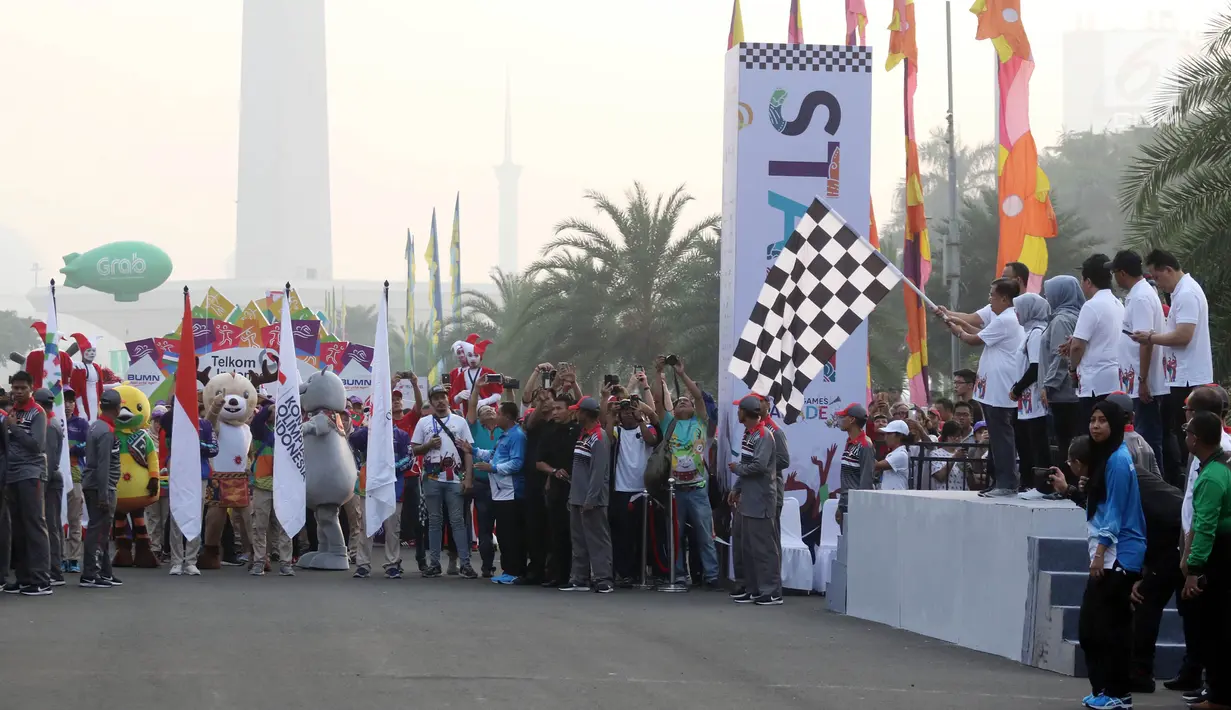 Wakil Presiden Jusuf Kalla didampingi Gubernur DKI Anies Baswedan mengibarkan bendera saat melepas parade Asian Games 2018 di Monas, Jakarta, Minggu (13/5). Parade Asian Games 2018 digelar di dua kota, Jakarta dan Palembang. (Liputan6.com/Arya Manggala)