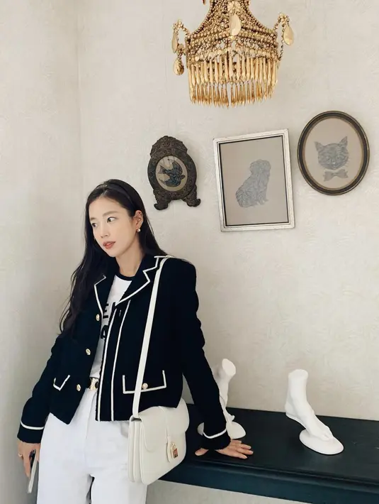 Ki Eunse dengan tampilan preppy, mengenakan blazer hitam, kaus putih, dan celana jeans putih, menyempurnakannya dengan sentuhan Celine Tabou Bag yang juga berwarna putiih. Foto: Document/Celine.