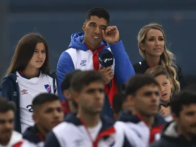Luis Suarez (tengah) menyeka matanya di antara putrinya Delfina (kiri) dan istrinya Sofia Balbi saat menonton video selama presentasinya sebagai pemain baru Nacional di Stadion Gran Parque Central, di Montevideo, pada 31 Juli, 2022. Luis Suarez kembali ke Uruguay untuk bergabung dengan Nacional, klub tempat ia memulai karirnya 17 tahun lalu sebagai salah satu striker terbaik di generasinya. (AFP/Pablo Porciuncula)