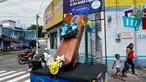 Warga berjalan dekat peti mati dengan tulisan, "Anda memutuskan, di rumah atau di dalam kotak ini", sebagai bagian dari kampanye pemerintah setempat di jalan-jalan kotamadya Escuintla, Guatemala City pada 21 Juli 2020. Kampanye itu sebagai upaya menghentikan penyebaran COVID-19. (Johan ORDONEZ/AFP)