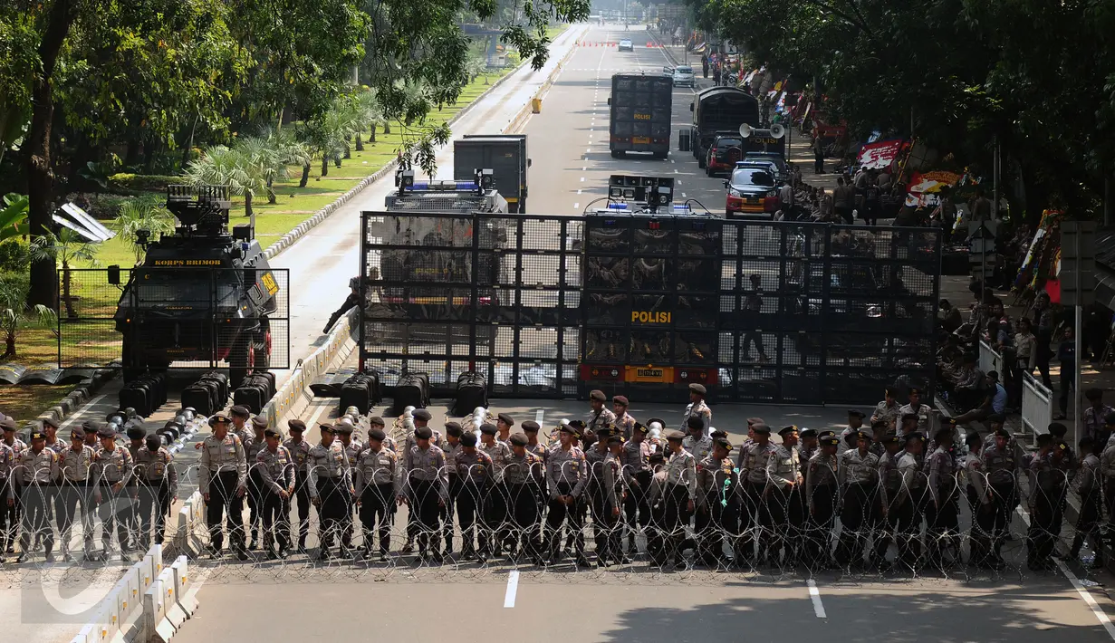 Ratusan petugas berjajar menutup Jalan Medan Merdeka Barat, Senin (1/5). Aksi perayaan Hari Buruh Internasional oleh ribuan buruh tertahan di depan Kementerian Pariwisata akibat penutupan Jalan medan Merdeka Barat. (Liputan6.com/Helmi Fithriansyah)