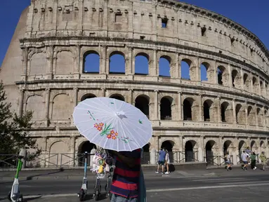 Seorang pria menjual payung dan kipas mini portabel di depan Colosseum saat suhu udara diperkirakan akan mencapai 39 derajat Celcius (102,20 Fahrenheit) di Roma, Italia, Sabtu (10/8/2024). (AP Photo/Gregorio Borgia)