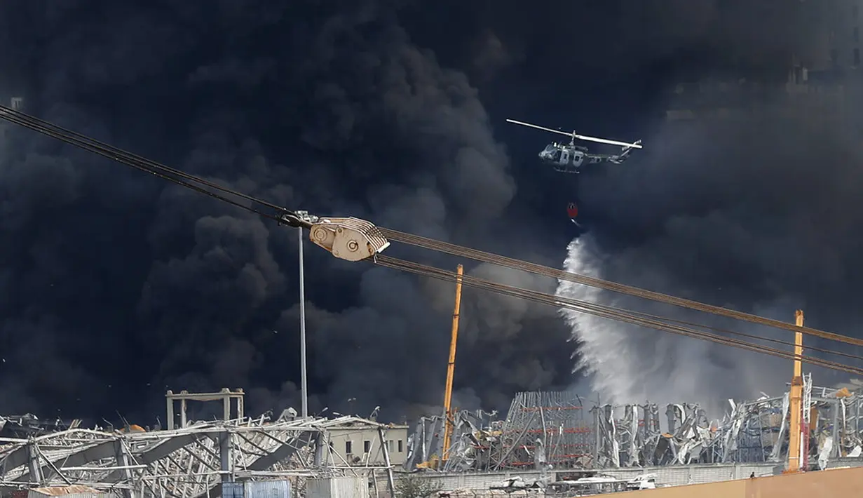 Helikopter tentara menjatuhkan air ke dalam api yang membakar gudang di Pelabuhan Beirut, Lebanon, Kamis (10/9/2020). Tentara Lebanon mengatakan kobaran api berkobar dari gudang penyimpanan minyak dan ban di area Bebas Pajak pelabuhan. (AP Photo/Hussein Malla)
