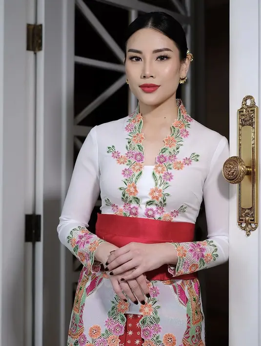 <p>Berwajah oriental, Angela tampil begitu menawan mengenakan kebaya model encim warna putih dengan aksen bordiran bunga warna-warni. [Instagram/@loritayoung_mua]</p>