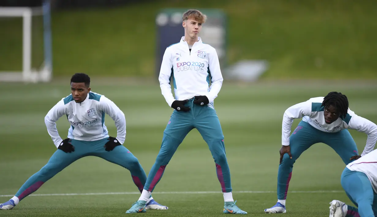 <p>Gelandang Manchester City, Cole Palmer (tengah) melakukan pemanasan saat mengambil bagian dalam sesi latihan di tempat latihan Manchester City di Manchester, barat laut Inggris, pada 25 April 2022. Manchester City akan bertanding melawan Real Madrid pada leg pertama semifinal Liga Champions. (AFP/Oli Scarff)</p>