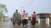 Personel gabungan patroli jalan kaki dan bagi sembako di kawasan Banjir Rob di Pemalang. (Foto: Liputan6.com/Polres Pemalang)