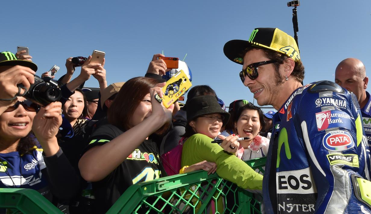 Valentino Rossi dikelilingi penggemarnya di paddock sebelum latihan bebas GP Jepang di Sirkuit Motegi, Jepang, (9/10/2015). (AFP Photo/Kazuhiro Nogi)