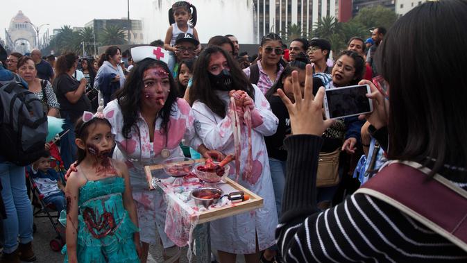 Sebuah keluarga berpose selama Zombie Walk di Mexico City, Minggu (11/11). Ratusan orang dengan penampilan yang seram serta mengenakan pakaian compang-camping berkumpul di pusat bersejarah ibu kota Meksiko dalam acara tahunan tersebut. (AP/Claudio Cruz)