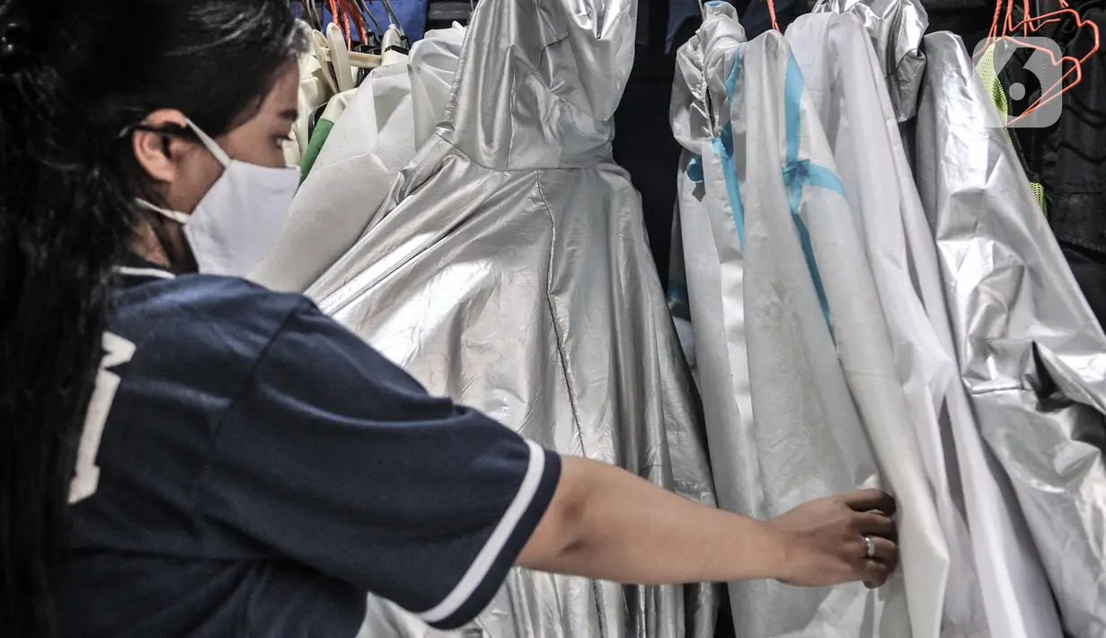 Pekerja menunjukkan berbagai jenis baju hazmat yang dijual di salah satu industri konveksi Pusat Industri Kecil (PIK), Jakarta, Rabu (30/12/2020). Dalam sehari, industri konveksi di PIK mampu memproduksi 50 buah baju hazmat tiap pekerja. (merdeka.com/Iqbal S. Nugroho)