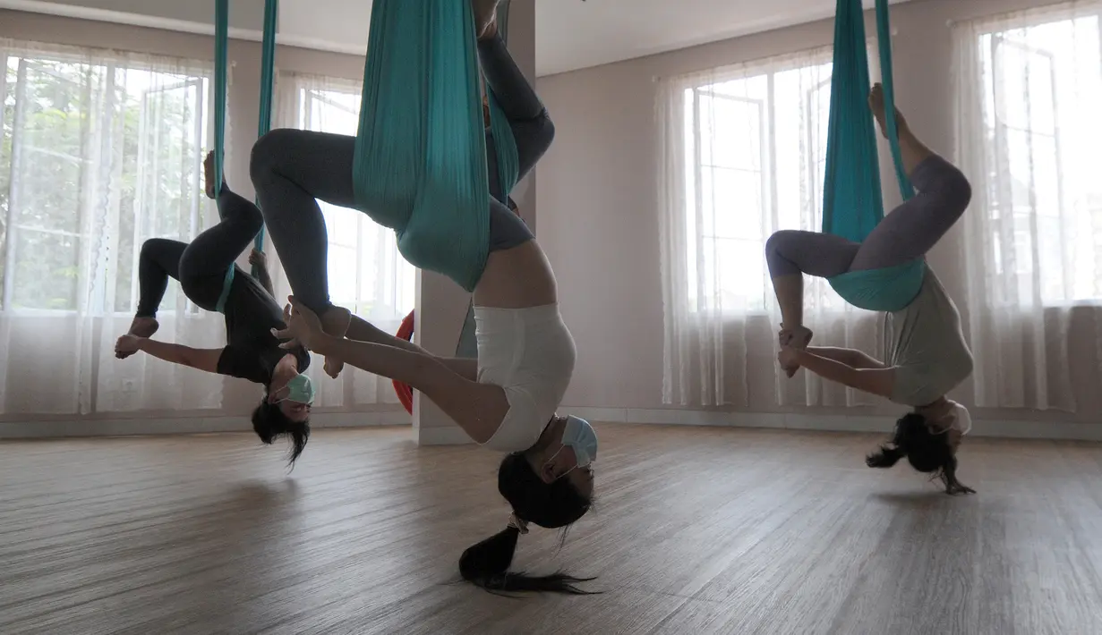 Para murid melakukan gerakan aerial yoga atau yoga udara di Aerial Jooga Studia, Kelapa Dua, Tangerang, Banten, Minggu (10/10/2021). Di masa pandemi, peminat olahraga yang berasal dari Amerika Serikat ini meningkat lebih dari 60 persen. (merdeka.com/Arie Basuki)