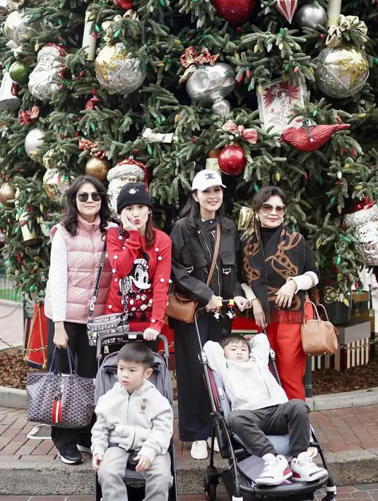 Sandra Dewi bersama keluarganya merayakan Natal di Amerika Serikat. Berfoto di depan pohon Natal yang besar, Sandra mengenakan jaket dan celana hitam. [@sandradewi88]