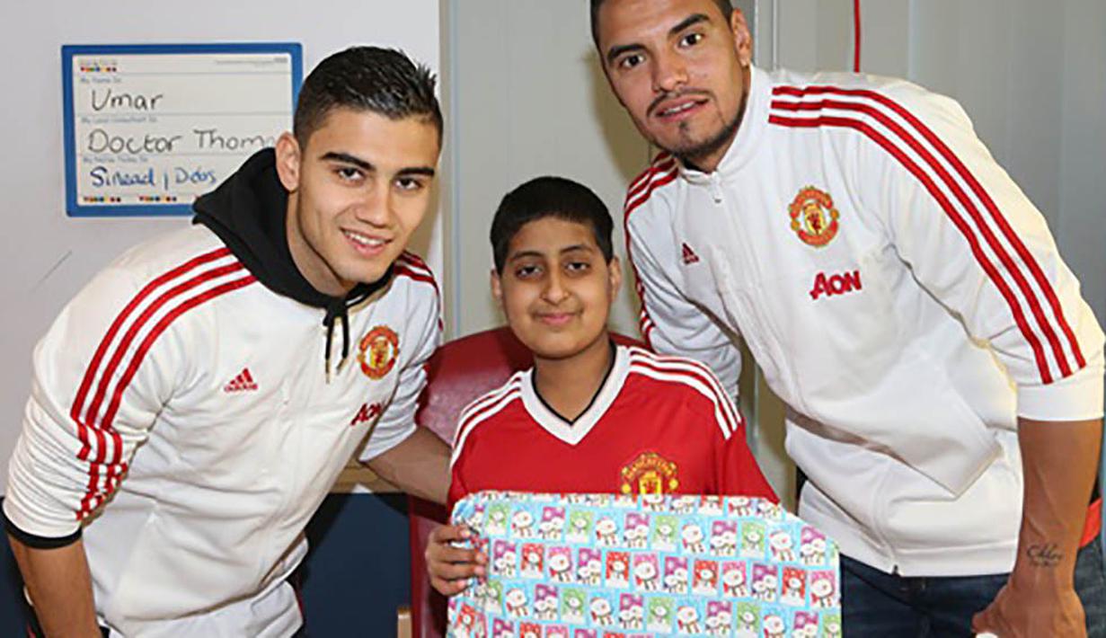 Kiper MU, Sergio Romero dan rekan setimnya, Andreas Perreira memberikan kado kepada pasien dari Rumah Sakit Royal Manchester Children. (www.manutd.com)