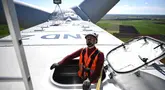 Seorang operator teknis mengamati dari sebuah palka di atap ruang mesin yang terletak di bagian atas turbin angin saat kegiatan pemeliharaan di Andilly-les-Marais dekat La Rochelle, Prancis barat pada tanggal 10 Maret 2025. (Christophe ARCHAMBAULT/AFP)