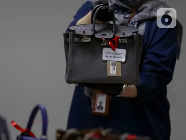 Petugas Komisi Pemberantasan Korupsi (KPK) menunjukkan salah satu tas mewah yang akan dilelang pada kegiatan Aanwijzing lelang barang rampasan hasil kasus korupsi yang ditangani di Rumah Penyimpanan Benda Sitaan Negara (Rupbasan), Jakarta, Kamis, (5/12/2024). (Liputan6.com/Herman Zakharia)