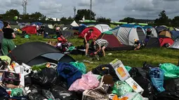 Setelah lima hari berpesta dan musik, orang-orang yang bersuka ria telah meninggalkan kemah di Worthy Farm, meninggalkan gunungan sampah plastik, tenda, dan tabung gas. (AFP/Oli Scarff)