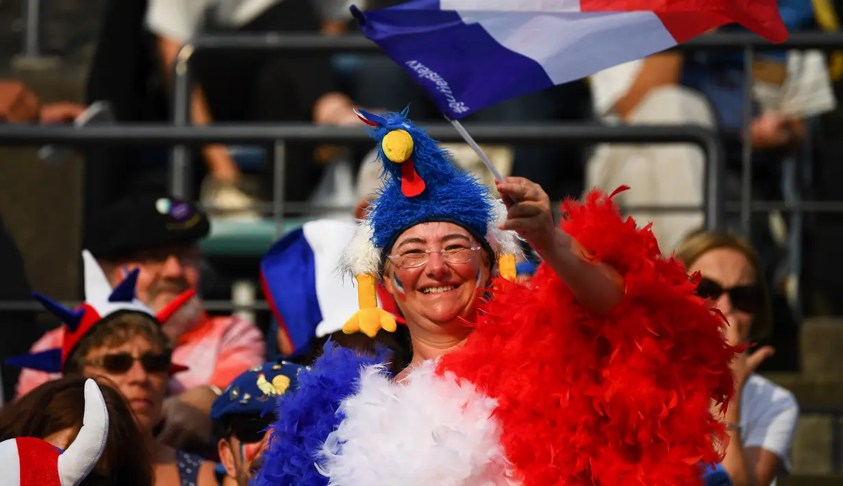 Seorang fans Prancis mengenakan kostum ayam mengibarkan bendera negaranya sebelum pertandingan Rugby World Cup Pool C antara Prancis dan Tonga di Stadion Kumamoto di Kumamoto (6/10/2019). (AFP Photo/Gabriel Bouys)