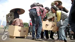 Petani perempuan yang disemen kakinya diangkat saat aksi mengecor kakinya di depan Istana Negara, Jakarta, Selasa (13/4). Aksi tersebut sebagai penolakan terhadap tambang dan pabrik semen di Pegunungan Kendeng, Jateng. (Liputan6.com/Faizal Fanani)
