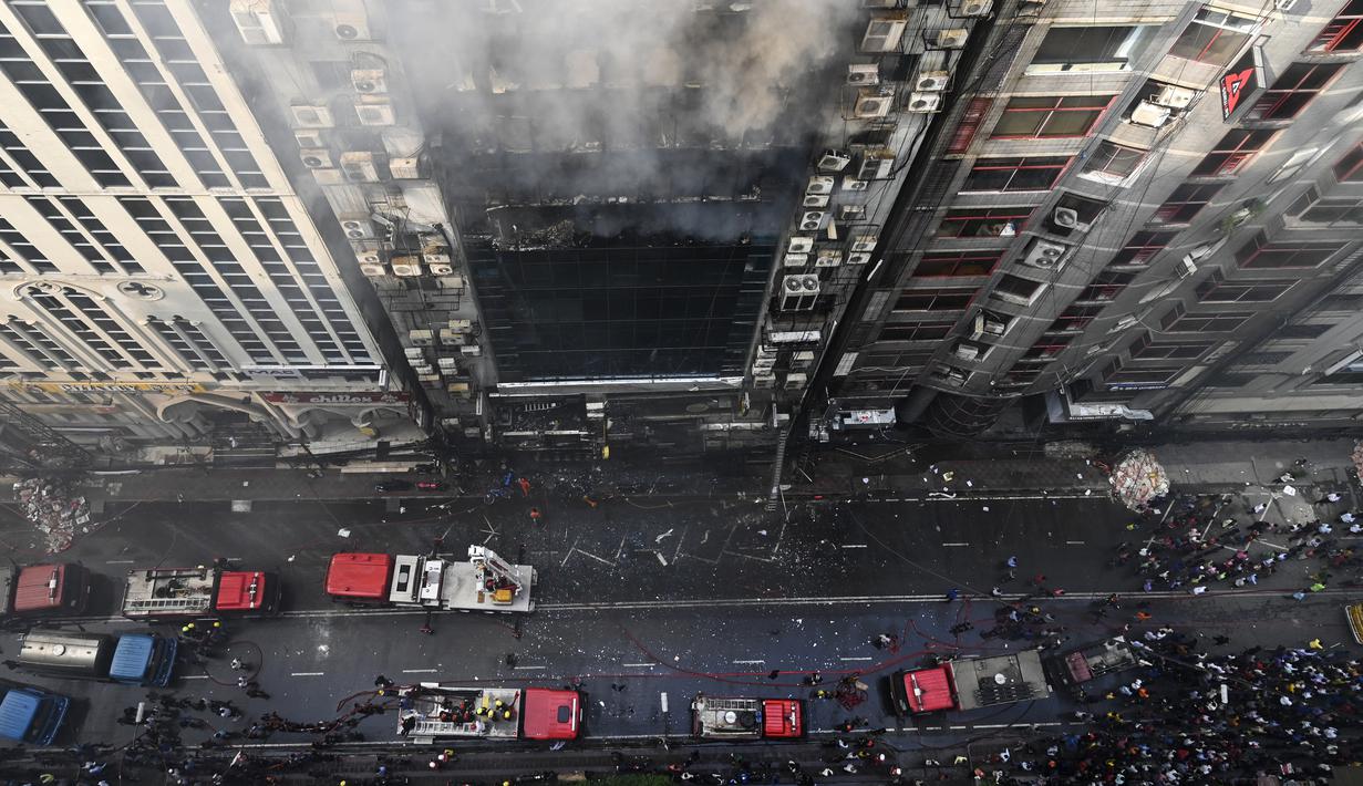 Petugas pemadam kebakaran Bangladesh berusaha memadamkan kobaran api di sebuah gedung perkantoran di Dhaka (28/3). Kebakaran besar melanda gedung perkantoran yang menewaskan sedikitnya lima orang dan lainnya masih terperangkap dalam gedung yang terbakar tersebut. (AFP/Munir Uzzaman)