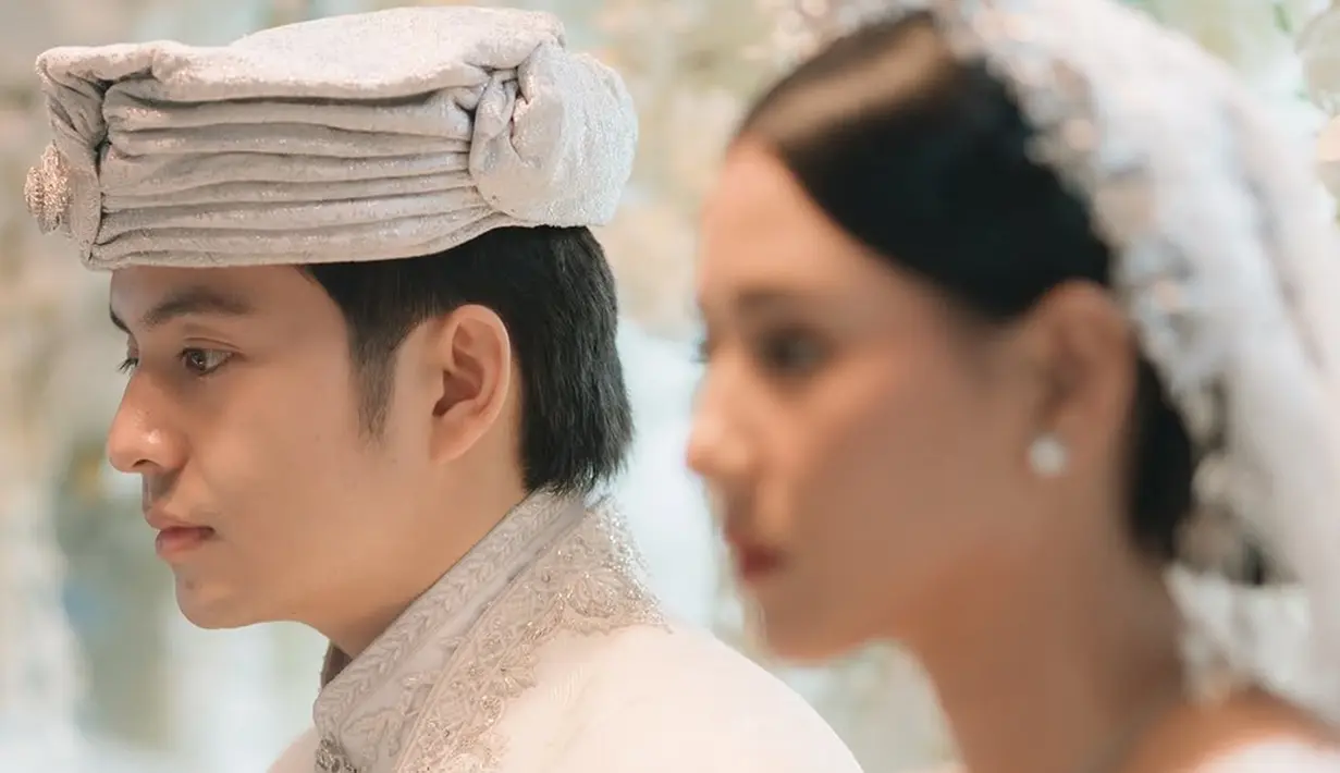 Meskipun detail pernikahan masih minim, terlihat bahwa acara berlangsung sederhana. Tema serba putih memberi kesan sakral dan elegan. Angga terlihat tampan menawan kenakan ikat kepala putih dari kain songket, serasi dengan busananya. (Liputan6.com/IG/@angga)